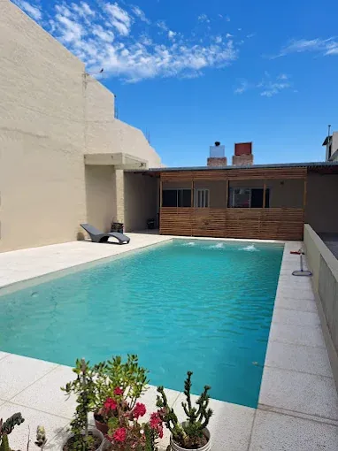 Pileta de Complejo Mar-Zoe de día, con reposeras y plantas